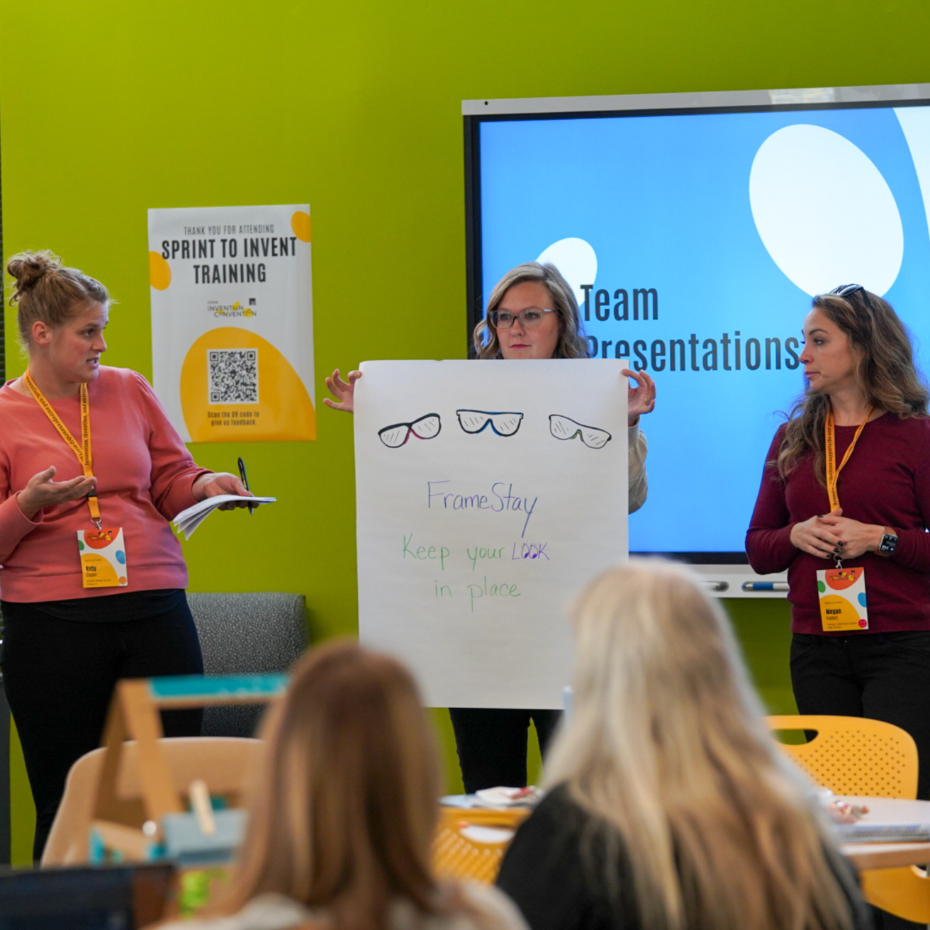 Teachers holding up a poster board, presenting.